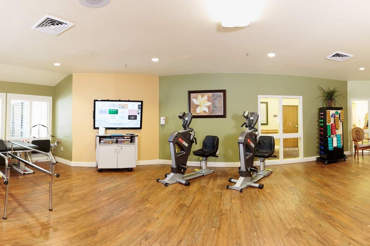 Rehabilitation gym with exercise equipment at Arlington Gardens Care Center.
