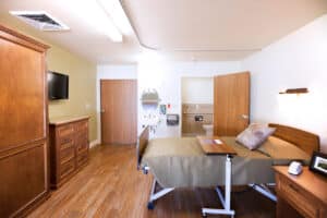 Single-bed resident room with TV and wardrobe at Arlington Gardens Care Cente