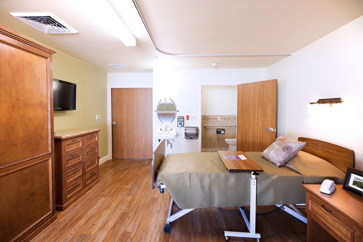Single-bed resident room with TV and wardrobe at Arlington Gardens Care Cente