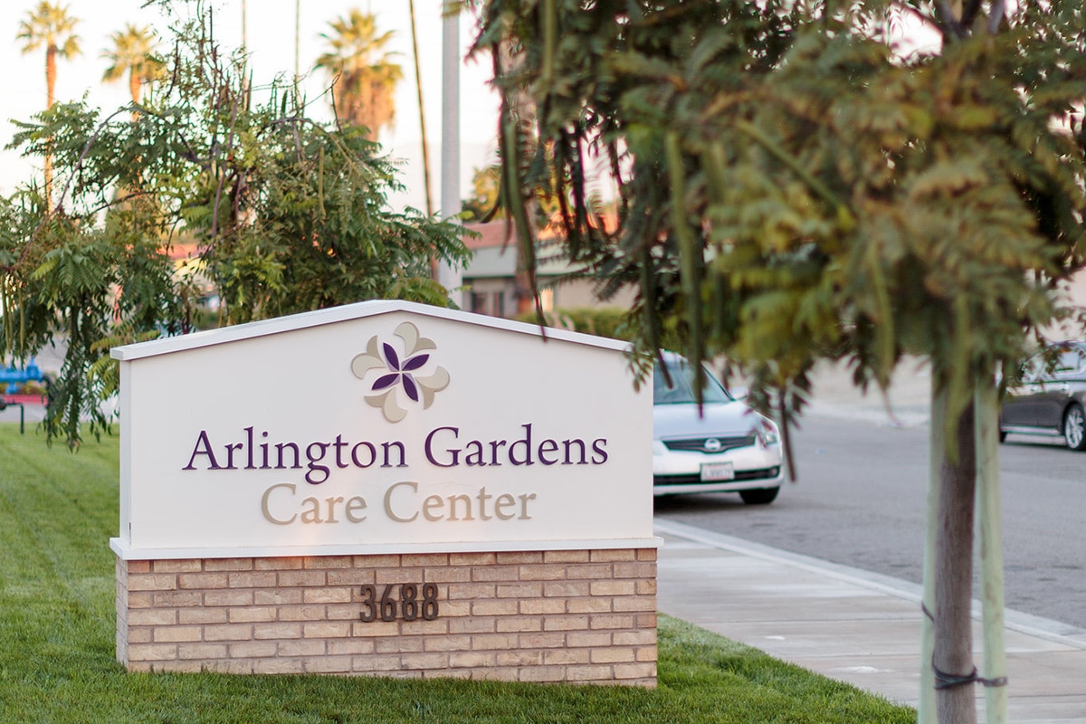 Sign for Arlington Gardens Care Center on a tree-lined street