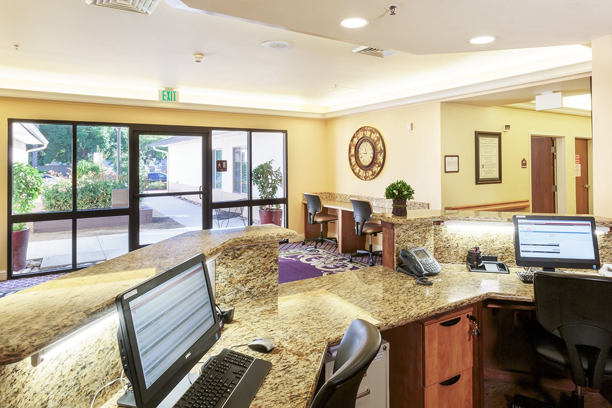 Reception area at Arlington Gardens Care Center with computer stations and front entrance.