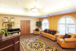 Lobby lounge at Arlington Gardens Care Center with sofas and arched windows
