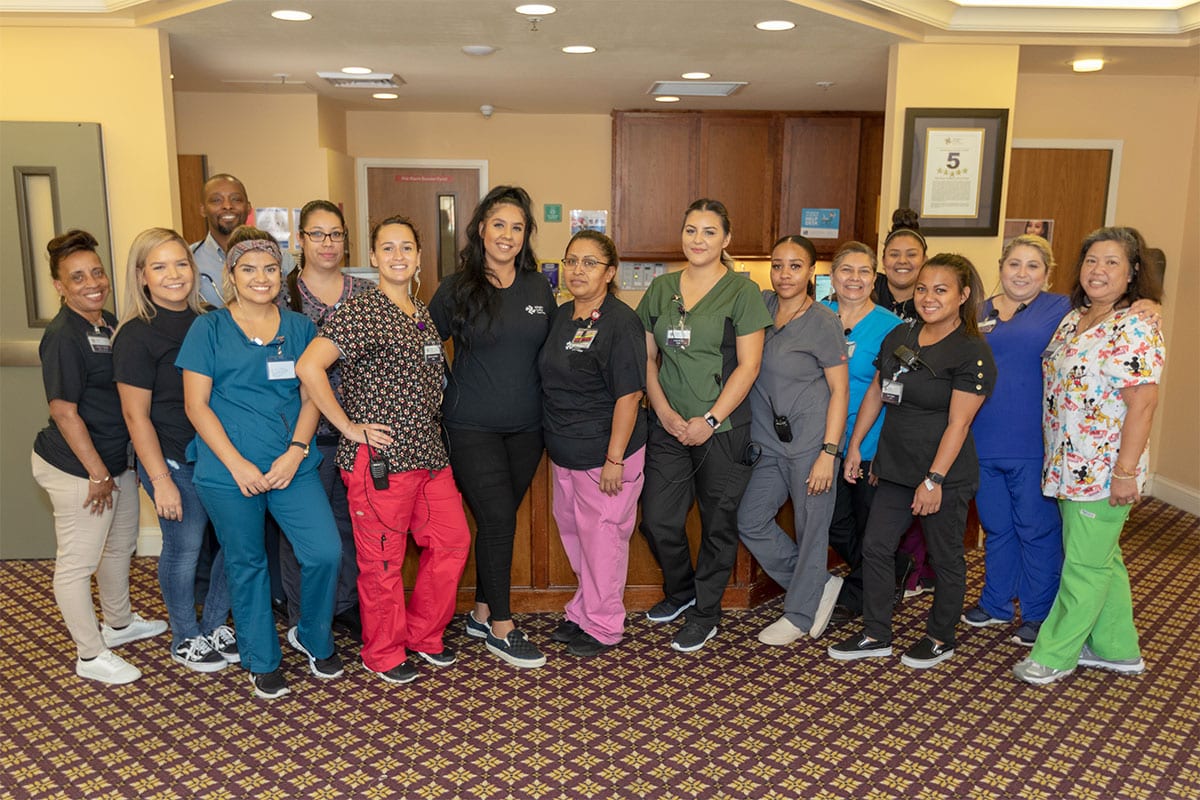 Group photo of Arlington Gardens Care Center staff in the facility lobby